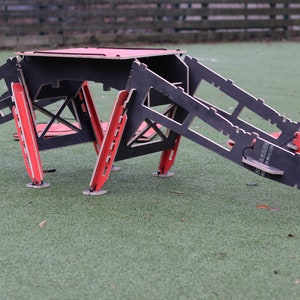 May include: A black and red wooden obstacle course for dogs. The course features a ramp, a platform, and a tunnel.