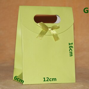 May include: A green gift bag with a yellow ribbon and a cut-out handle. The bag measures 6 inches by 12 inches by 16 inches.