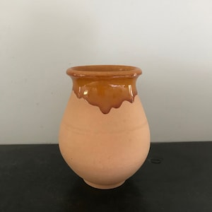 Op de afbeelding: Een terracotta vaas met een bruine geglazuurde rand. De vaas is rond en heeft een bolle vorm.