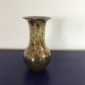 May include: A green and brown ceramic vase with a flared top and a rounded body.