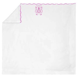 Puede incluir: Manta blanca con un borde rosa festoneado y un monograma rosa de la letra "B" en forma de corazón.