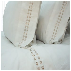 May include: Two white pillowcases with a decorative pattern of brown circles along the edges.