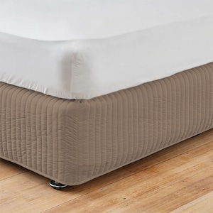 Peut inclure: Une jupe de lit matelassée beige avec des coutures verticales. La jupe est faite d'un tissu doux et confortable et est conçue pour s'adapter à un lit standard.