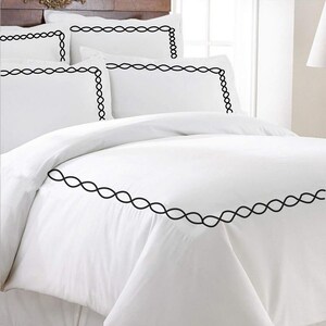 Puede incluir: Juego de cama blanco con ribete bordado negro. El juego incluye una funda n&oacute;rdica y dos fundas de almohada.