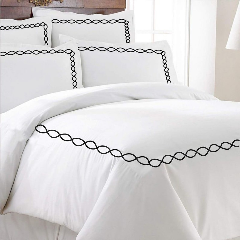 Puede incluir: Juego de cama blanco con ribete bordado negro. El juego incluye una funda n&oacute;rdica y dos fundas de almohada.