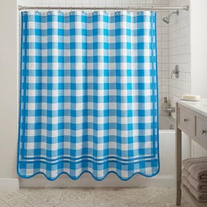 May include: A shower curtain featuring a bright blue and white gingham check pattern. The curtain hangs from a silver rod with rings and has a scalloped bottom edge with two horizontal blue stripes running along the lower portion of the fabric.