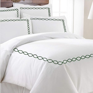 Puede incluir: Juego de cama blanco con un borde bordado verde. El juego incluye una funda n&oacute;rdica y fundas de almohada.