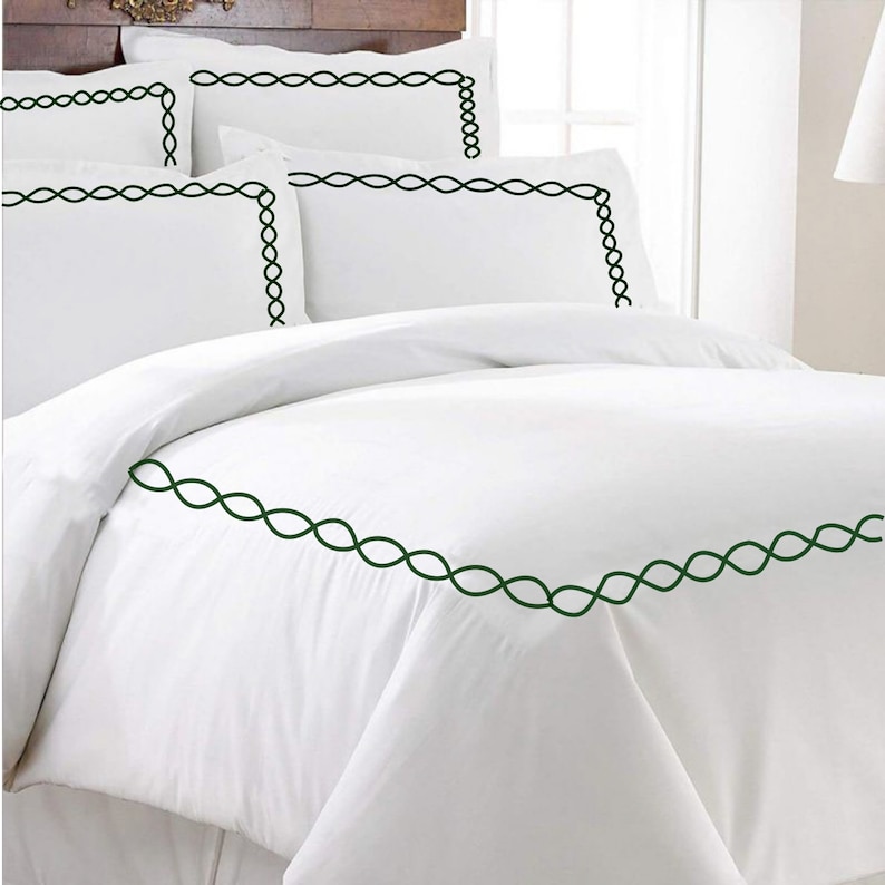 Puede incluir: Juego de cama blanco con un borde bordado verde. El juego incluye una funda n&oacute;rdica y fundas de almohada.