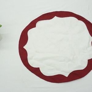 May include: White round table runner with a scalloped edge and a burgundy border.