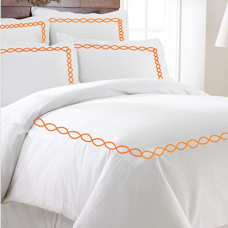 Puede incluir: Juego de cama blanco con ribete bordado naranja. El juego incluye una funda n&oacute;rdica y varias fundas de almohada.