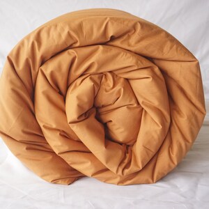May include: A rolled up mustard yellow duvet cover. The duvet cover is made of a soft, comfortable fabric and is perfect for a cozy night's sleep.