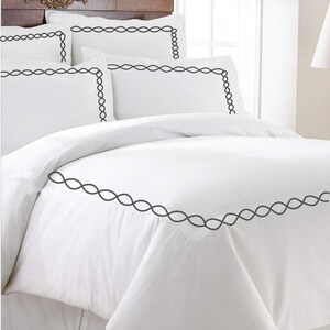Puede incluir: Juego de cama blanco con un borde bordado negro. El juego incluye una funda n&oacute;rdica y fundas de almohada.