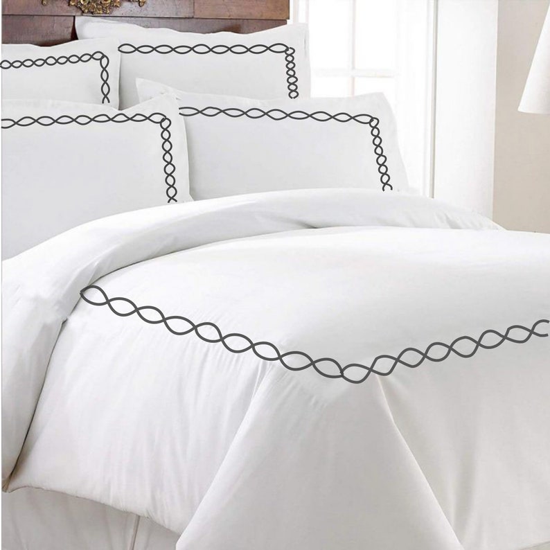Puede incluir: Juego de cama blanco con un borde bordado negro. El juego incluye una funda n&oacute;rdica y fundas de almohada.