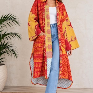 May include: A long-sleeved, knee-length duster coat featuring a patchwork design in vibrant shades of red and yellow with intricate floral and geometric patterns. The garment has a collared neckline, a button-down front, and two side pockets.