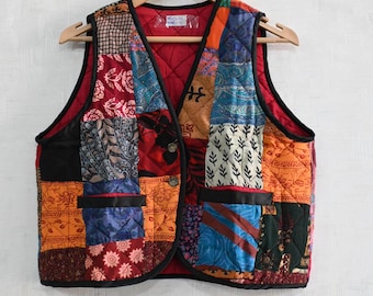 May include: A patchwork vest with a quilted red lining and black trim. The vest features a variety of patterned fabrics in shades of red, orange, blue, and green. It has two pockets and a button closure.