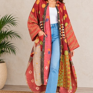 May include: A long-sleeved, knee-length patchwork duster coat featuring a vibrant mix of red, orange, green, and beige fabric panels with intricate kantha stitching, a collared neckline, front button closure, and two side pockets.