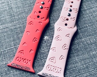 May include: Two watch bands with a heart pattern. One is pink and the other is red. Both bands have the word "OXOX" printed on them.