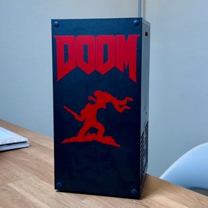 May include: A black computer case with a red DOOM logo and a red silhouette of a demon and a soldier on the front.