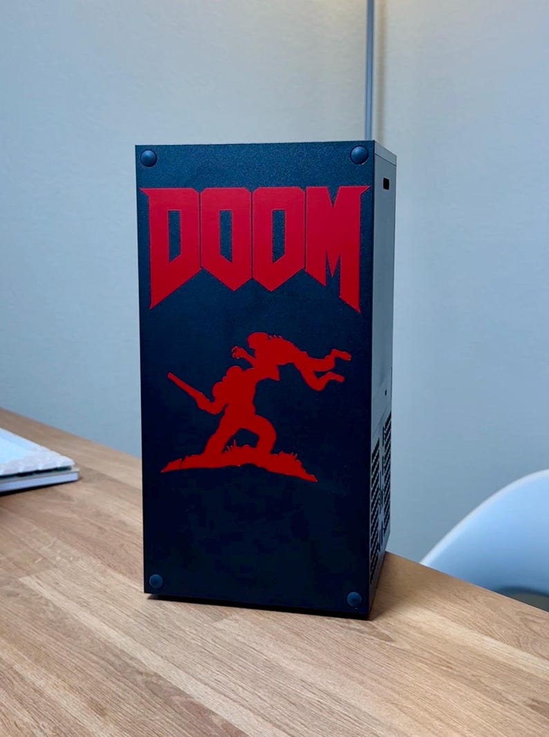 May include: A black computer case with a red DOOM logo and a red silhouette of a demon and a soldier on the front.