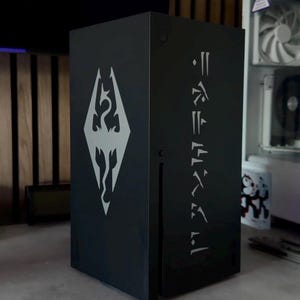 May include: A black rectangular box with a white emblem and text. The emblem is a stylized dragon within a diamond shape. The text is in a vertical, stylized font. The box is on a gray surface.