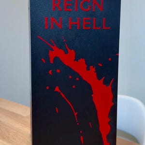May include: Black box with the words "Reign in Hell" in red lettering. The box has a red splatter design.