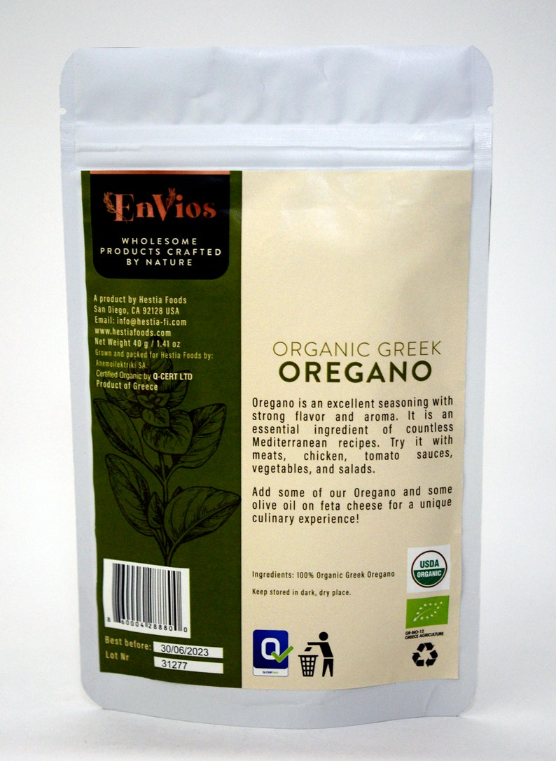 May include: A white resealable pouch with a green and brown label. The label reads "Envios Wholesome Products Crafted by Nature" and "Organic Greek Oregano". The label also includes a description of the product and its uses. The pouch is labeled with a USDA Organic seal.