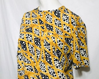 May include: A white, black, and gold patterned blouse with a geometric design. The pattern features black polka dots, gold bamboo-like lines, and black geometric shapes.