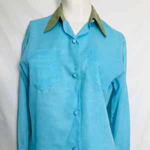 May include: A light blue long-sleeved button-down shirt with a green collar and cuffs.
