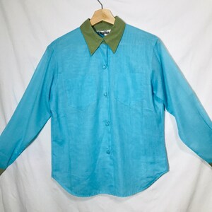 May include: A light blue long-sleeved button-down shirt with a green collar and cuffs.