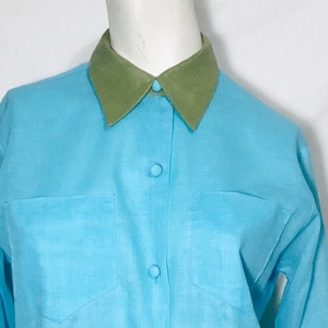 May include: A light blue long-sleeved button-down shirt with a green collar and cuffs.
