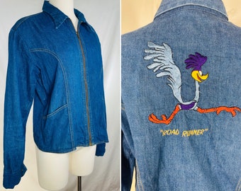 May include: A blue denim jacket with a zipper closure and a Road Runner cartoon embroidered on the back. The Road Runner is running and the text "Road Runner" is below it.