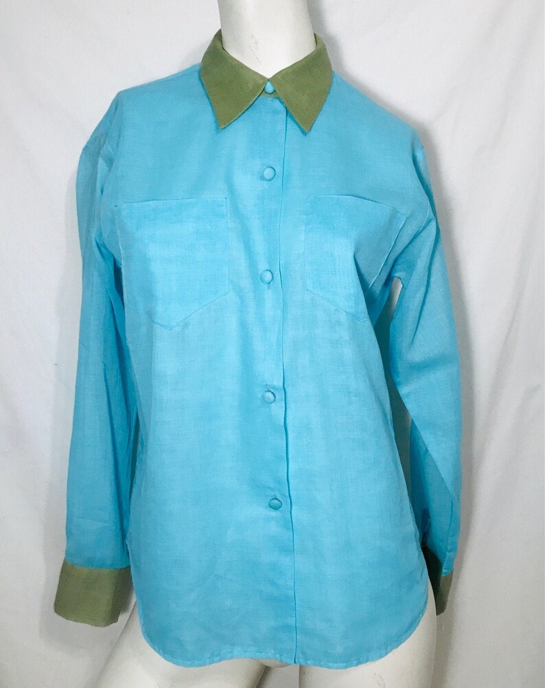 May include: A light blue long-sleeved button-down shirt with a green collar and cuffs.