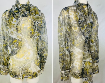 May include: A sheer blouse with long sleeves and a floral print in shades of green, yellow, and white. The blouse has a tie at the neck and is made of a lightweight fabric.