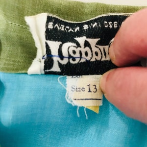 May include: A blue and green children's dress with a black label that says "Wigwam" and "Size 13".
