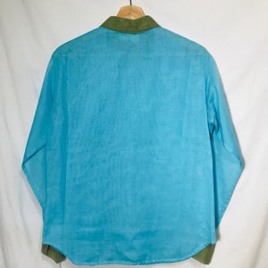May include: A light blue long-sleeved shirt with a green collar. The shirt is made of a lightweight fabric.