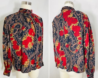 May include: A long-sleeved blouse with a high neck and a paisley pattern featuring red roses. The blouse is made of a soft, flowing fabric.