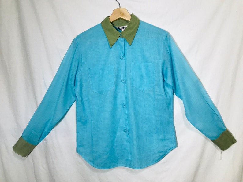 May include: A light blue long-sleeved button-down shirt with a green collar and cuffs.