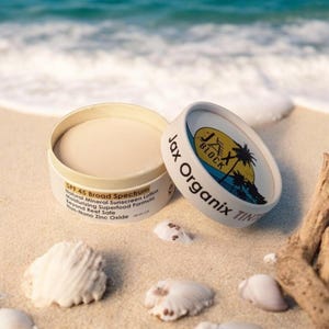 mineral sunscreen, open jar, sitting on sandy beach