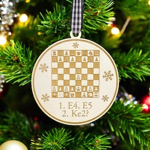 May include: A wooden Christmas ornament shaped like a chessboard with a white and brown checkered pattern. The ornament has a black and white ribbon for hanging and the text "1. E4, E5 2. Ke2?" printed on the bottom.