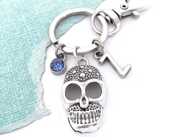 May include: Silver skull keychain with a blue rhinestone, a silver charm with the letter 'Z' and a silver key ring.