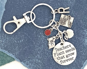 May include: Silver keychain with a charm that reads "Teachers Plant Seeds That Grow Forever". The keychain also features charms with the letters "ABC", a red gemstone, a heart, an apple, and a charm that reads "Best Teacher Ever".
