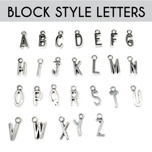 May include: Silver block style alphabet letter charms. The letters are A through Z.