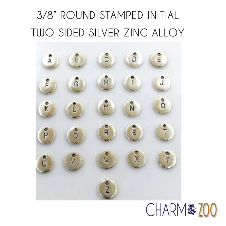 May include: A set of 26 silver-toned metal alphabet charms, each with a letter stamped on the front. The charms are 3/8 inch in diameter and have a small loop at the top for attaching to jewelry or other crafts.