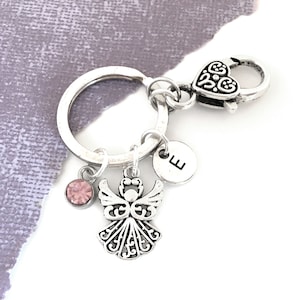 May include: Silver angel charm keychain with a pink crystal, a silver letter E charm, and a silver heart-shaped clasp.