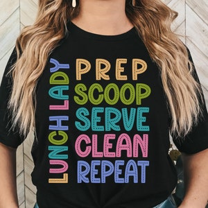 May include: Black t-shirt with the text "Lunch Lady" in pink, "Prep" in yellow, "Scoop" in green, "Serve" in blue, "Clean" in pink, and "Repeat" in purple.