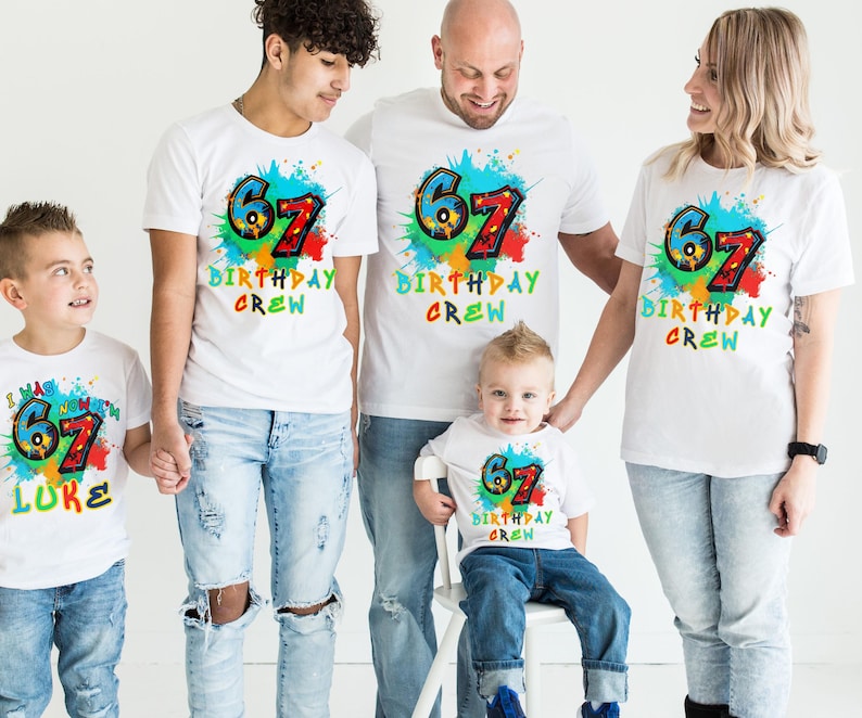 May include: A group of five people wearing matching white t-shirts with a colorful "67 BIRTHDAY CREW" design. The design includes the number 67 in blue and red, with a splash of colors. One shirt says "I HAS NOW 67 LUKE".