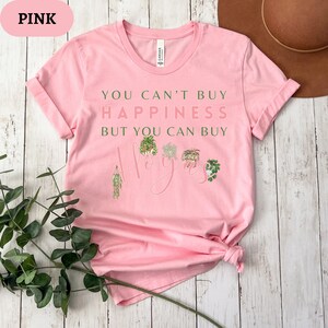 May include: Pink t-shirt with the text "You can't buy happiness but you can buy hoyas" and a graphic of several hoya plants.