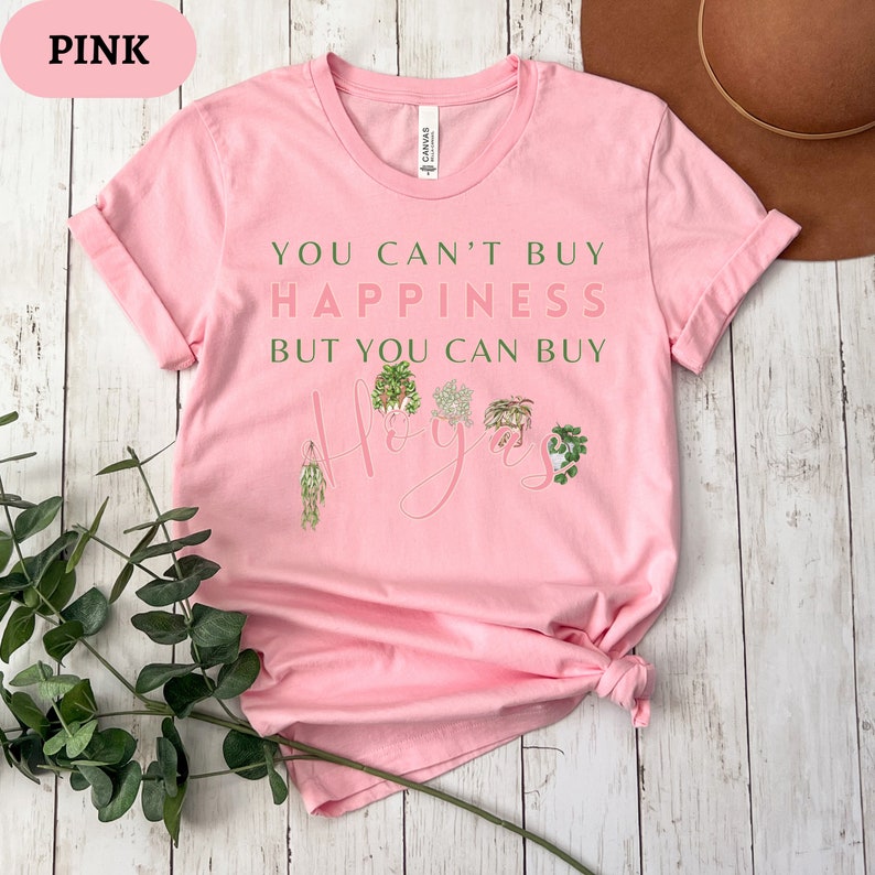 May include: Pink t-shirt with the text "You can't buy happiness but you can buy hoyas" and a graphic of several hoya plants.