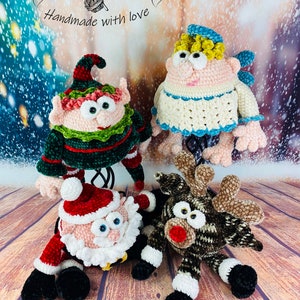 May include: Four crocheted Christmas characters: a green elf, a white angel, a red Santa Claus, and a brown reindeer. Each character has large, googly eyes and a whimsical expression. The characters are sitting on a wooden surface with a snowy background.
