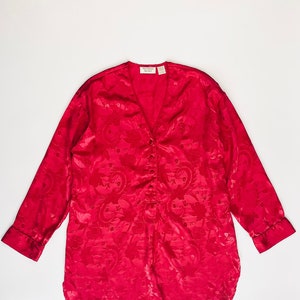 May include: A red satin long-sleeved shirt with a floral pattern and a button-up front. The shirt has a V-neck and a relaxed fit. The label reads "Victoria's Secret".
